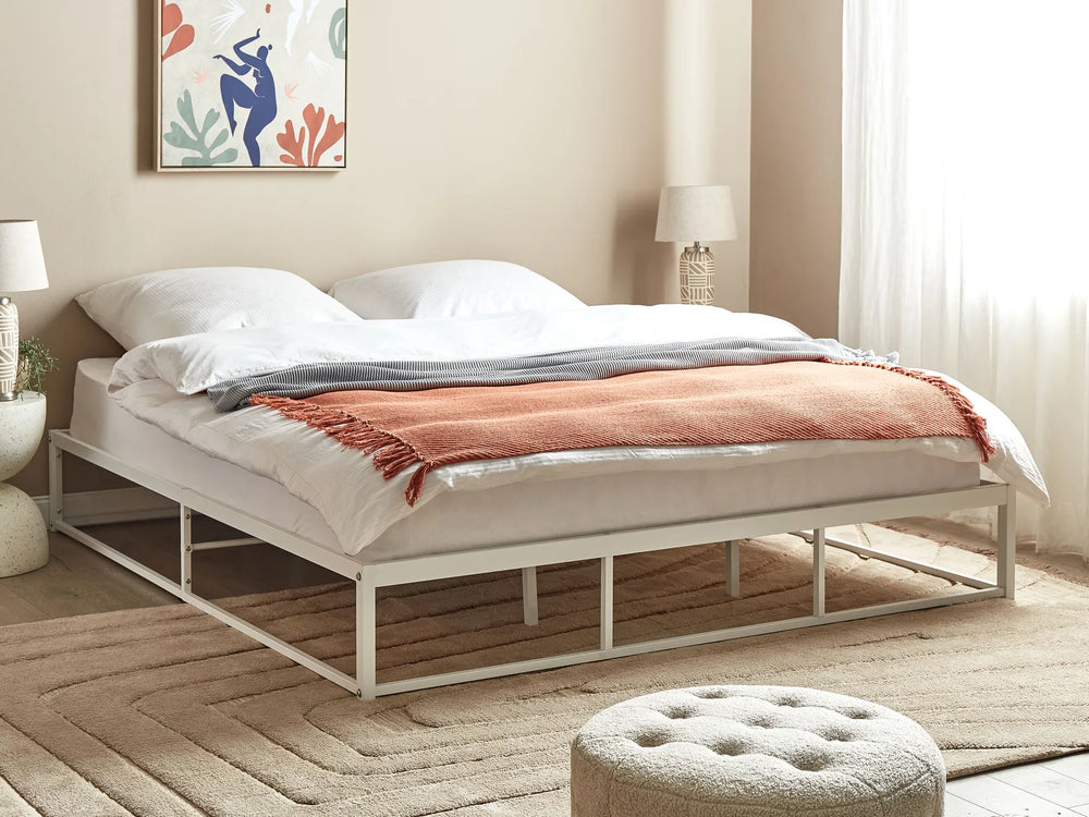 Bedroom with a bed featuring white bedding and a pink blanket, with a lamp and artwork on the wall.