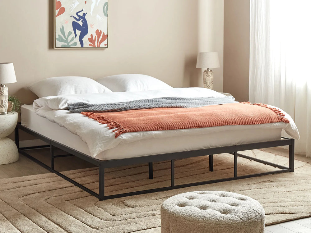 Bedroom with a bed featuring white bedding and an orange blanket, surrounded by decor elements.