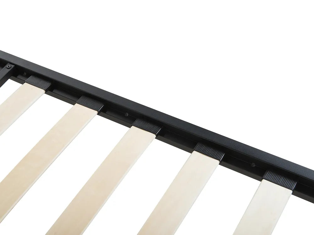 Close-up of a crib rail with black metal frame and beige wooden slats on a white background