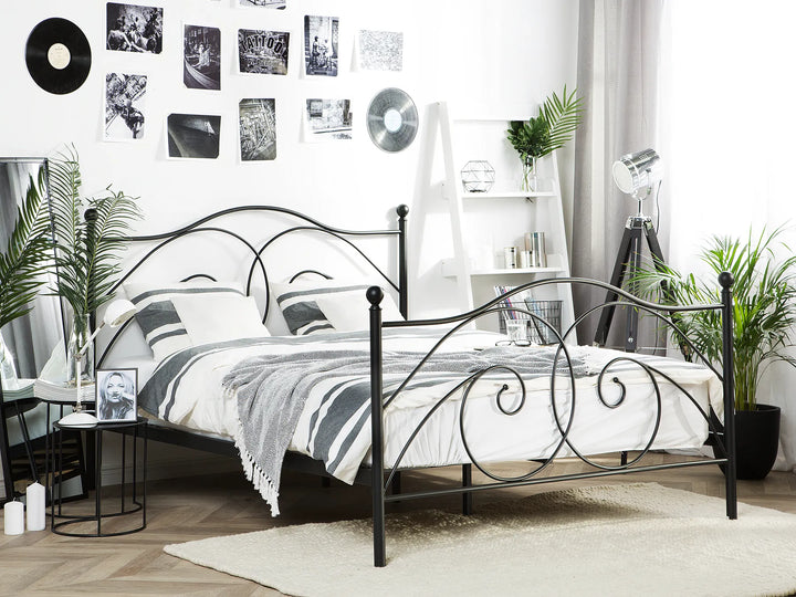 Bedroom with a black metal bed frame, white bedding, and decorative elements.