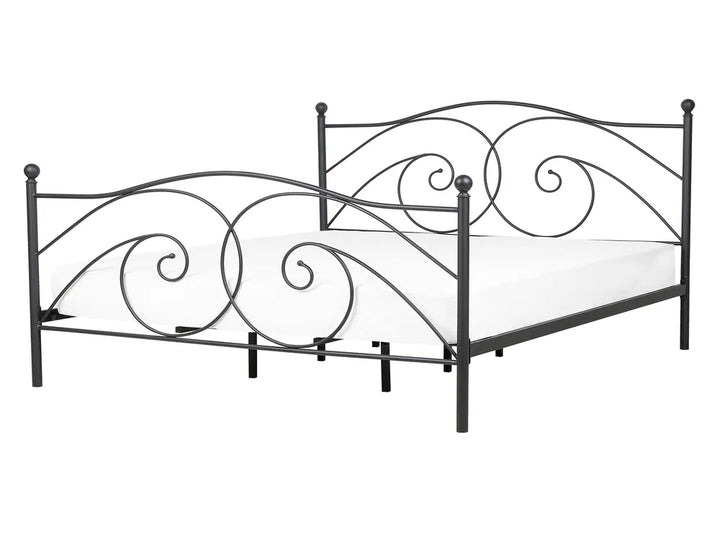Decorative metal bed frame with intricate designs on a white background