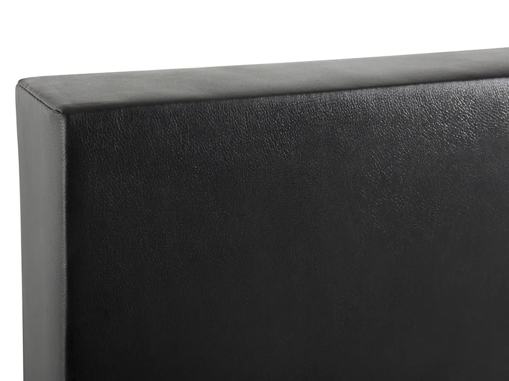 Close-up of a black upholstered headboard corner on a white background