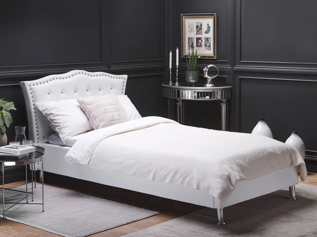 White upholstered bed in a darkly paneled room with decorative elements.
