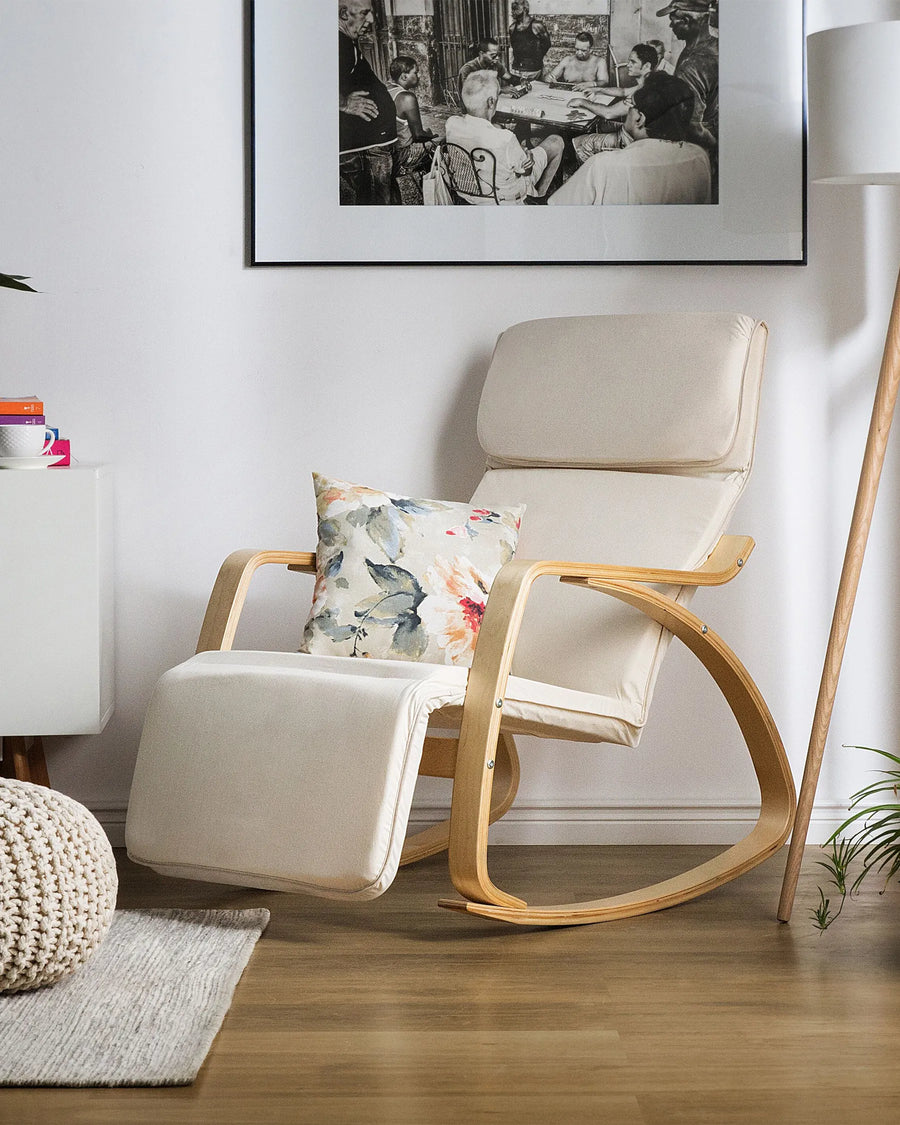 Beige rocking chair with a floral pillow in a room with a framed picture on the wall.