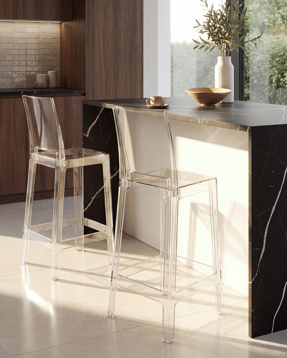 Two modern transparent acrylic bar stools with clear backs and seats, positioned at a kitchen island with a black marble countertop and dark wood cabinetry.