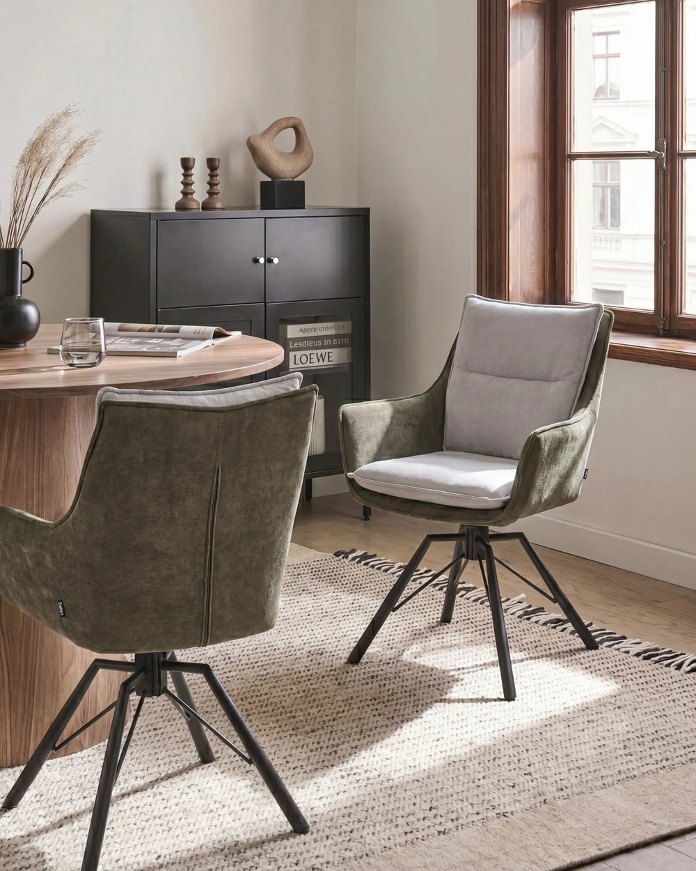 Two modern swivel dining chairs in a styled dining room setting. One chair is upholstered in textured olive green velvet with a white seat cushion, and the other is shown from the back in olive green velvet.