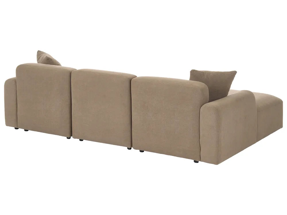A four-seater modular upholstered sofa in a warm taupe-beige fabric, featuring two matching throw pillows, shown from a three-quarters angle against a plain white background.