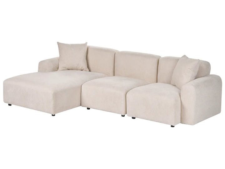 A modern sectional sofa in a light beige fabric, featuring a left-facing chaise lounge, three back cushions, and two loose throw pillows, shown against a plain white background.