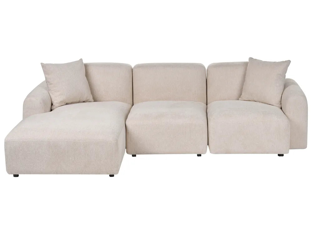 A modern three-seater sectional sofa with a left-facing chaise lounge, upholstered in a textured light beige fabric, featuring two matching throw pillows, shown against a plain white background.