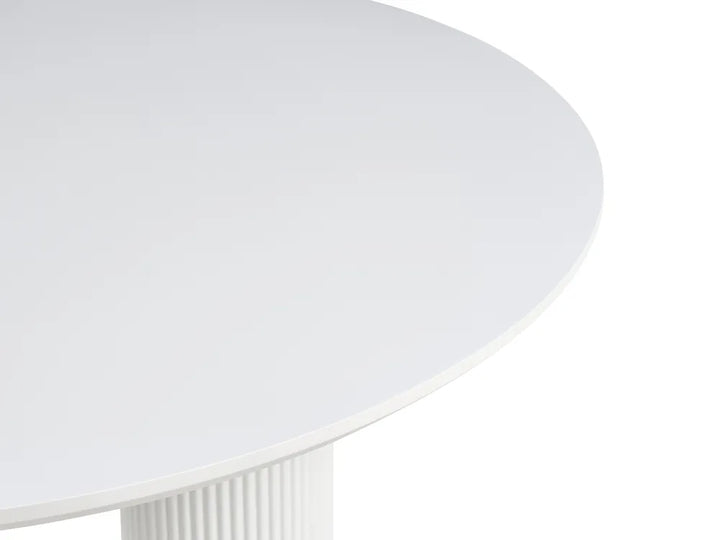 Close-up of a white round table showing the smooth tabletop surface and part of a fluted pedestal base against a white background.