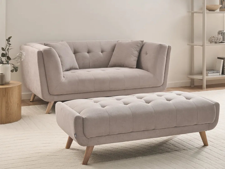 Beige sofa and ottoman in a living room setting with a neutral color palette.