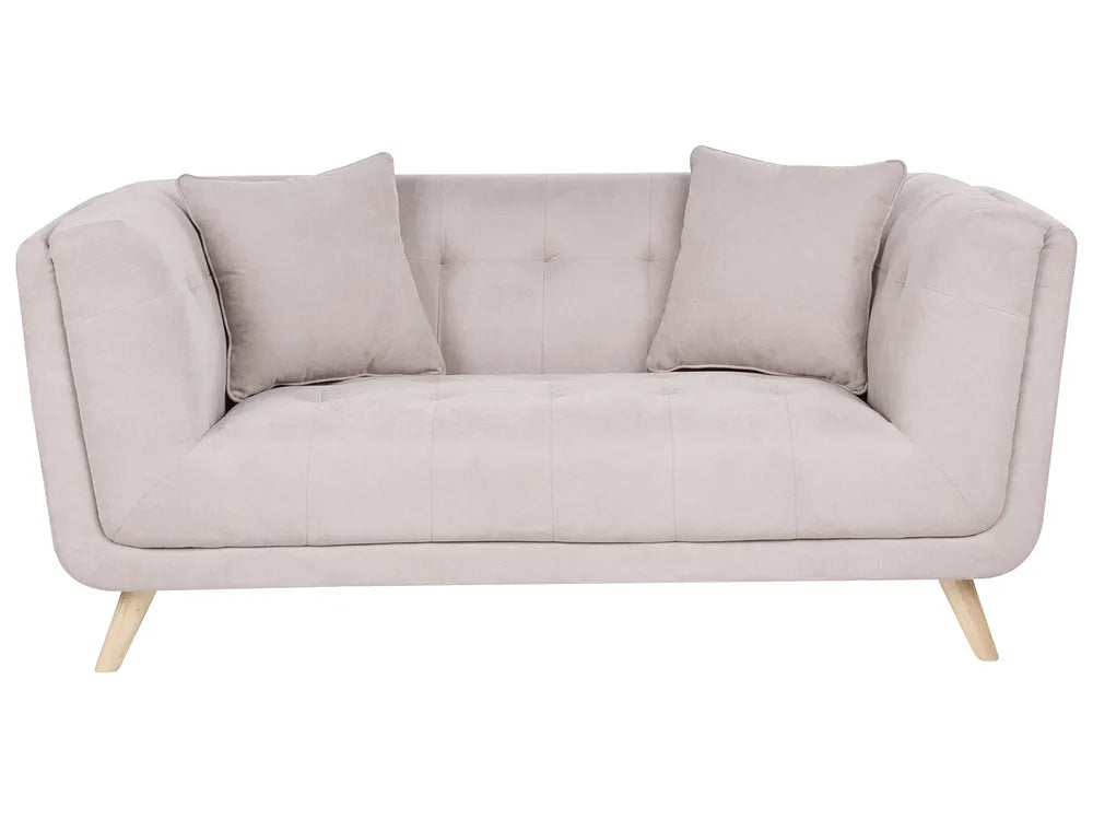 A light beige upholstered loveseat with two matching throw pillows and light wood legs, shown against a plain white background.