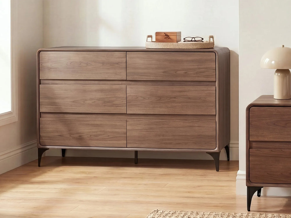A mid-century modern six-drawer dresser in a warm walnut wood finish, styled in a bedroom setting next to a matching nightstand.