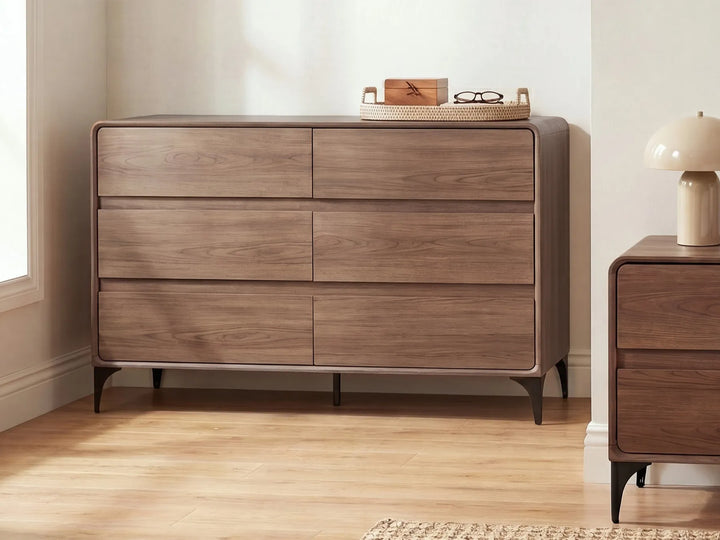 A mid-century modern six-drawer dresser in a warm walnut wood finish, styled in a bedroom setting next to a matching nightstand.
