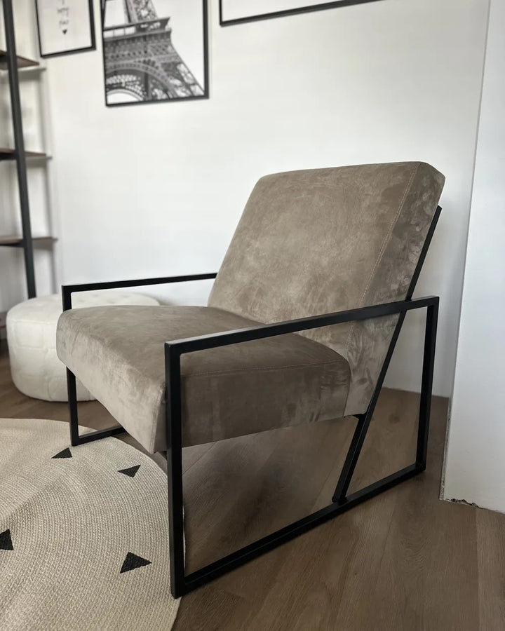 Gray armchair with black metal frame in a room with a white wall and geometric rug.