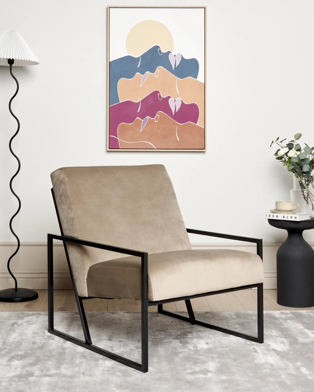 Beige armchair with black metal frame in a room with abstract art on the wall.