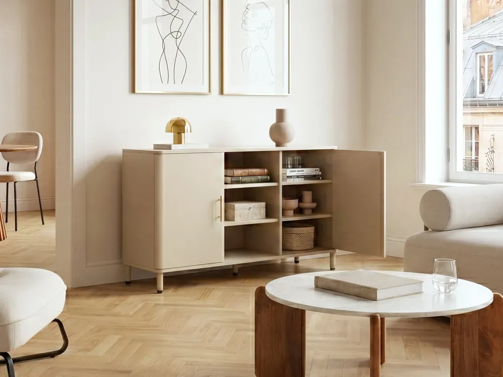 A modern beige sideboard cabinet with open doors and shelves, styled in a bright, minimalist living room with light wood floors, a white coffee table, and neutral decor.