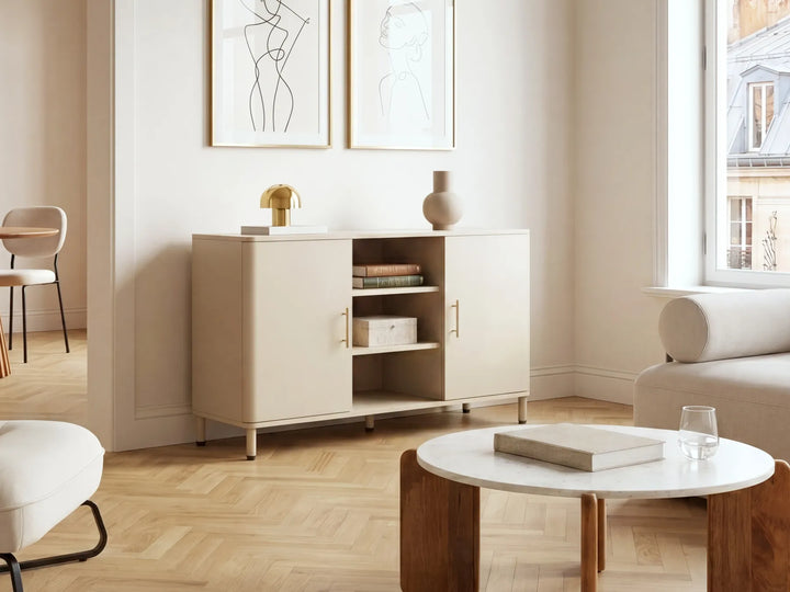 A modern beige sideboard cabinet with open doors and shelves, styled in a bright, minimalist living room with light wood floors, a white coffee table, and neutral decor.