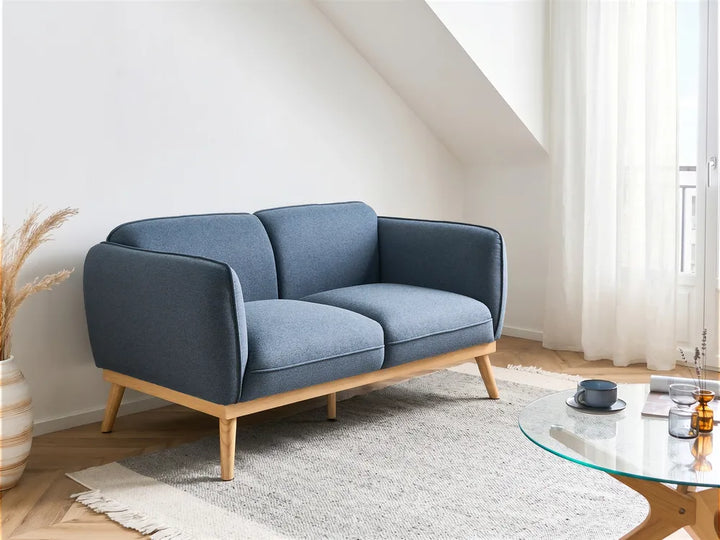 Blue sofa in a living room with a glass coffee table and decor items.