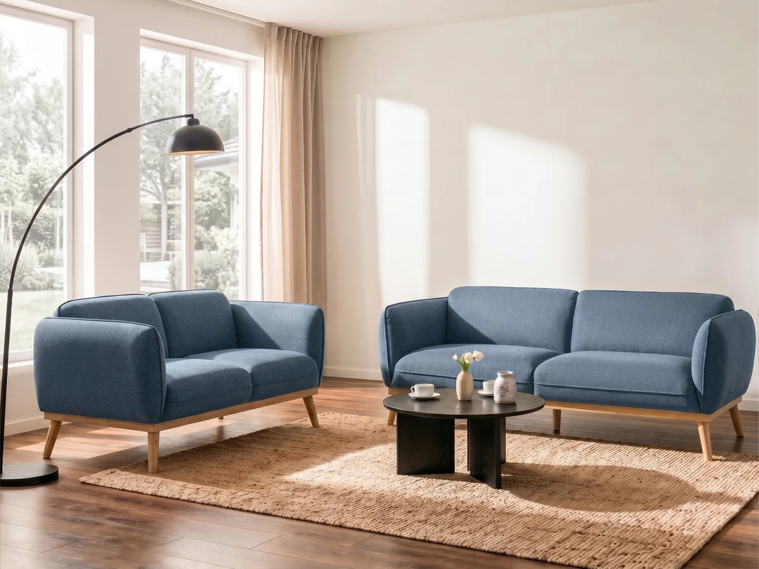 Blue sofa set in a modern living room with large windows and a rug.