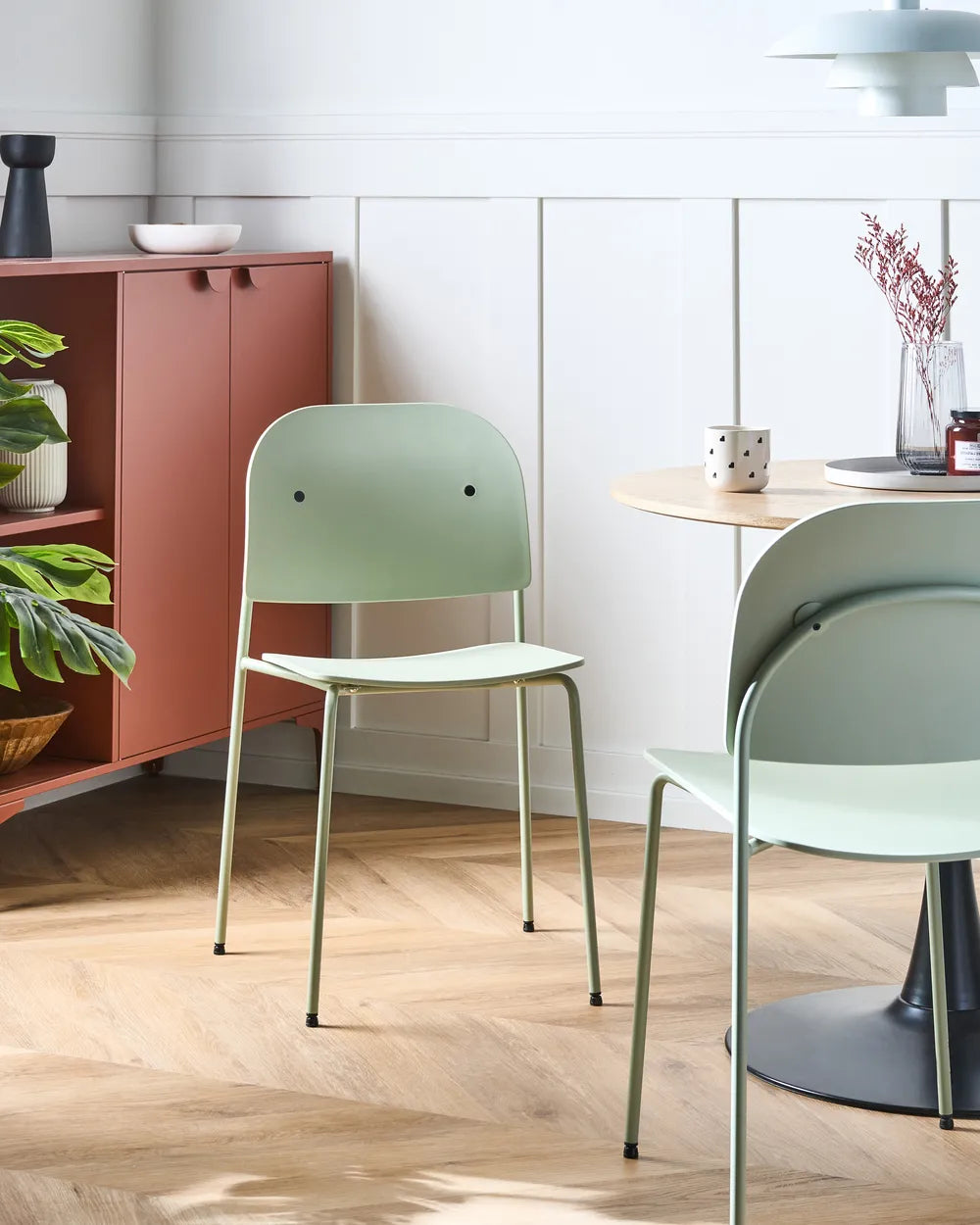 Green chairs in a modern room with a cabinet and decor items.