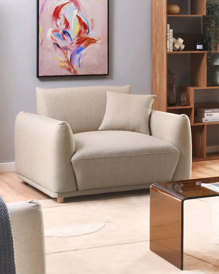 Beige armchair in a living room with a colorful abstract painting on the wall.