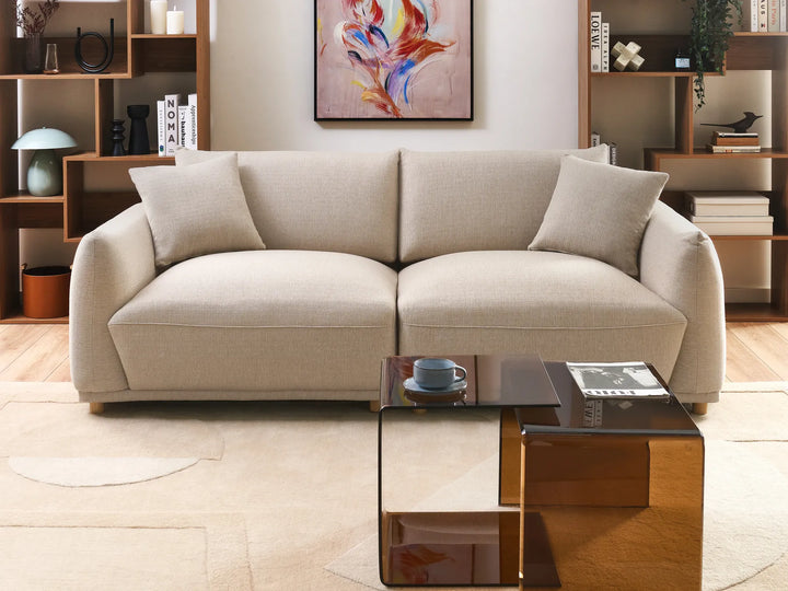Beige sofa in a living room with a glass coffee table and decorative items.