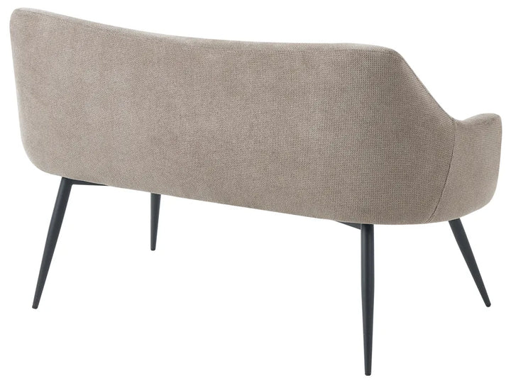 A modern upholstered bench with a curved backrest and armrests, upholstered in a textured light beige fabric and supported by four tapered black metal legs, shown from a three-quarters angle against a plain white background.