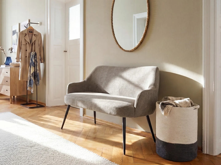 Gray sofa in a room with a coat, mirror, and basket.