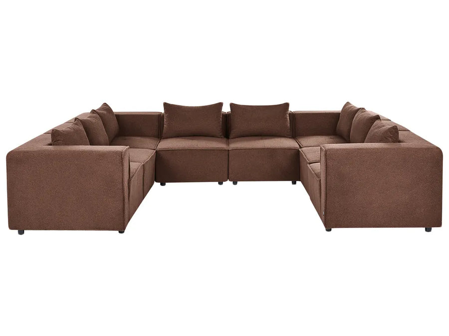 A brown fabric sectional sofa with multiple matching back cushions, shown from the front on a plain white background.