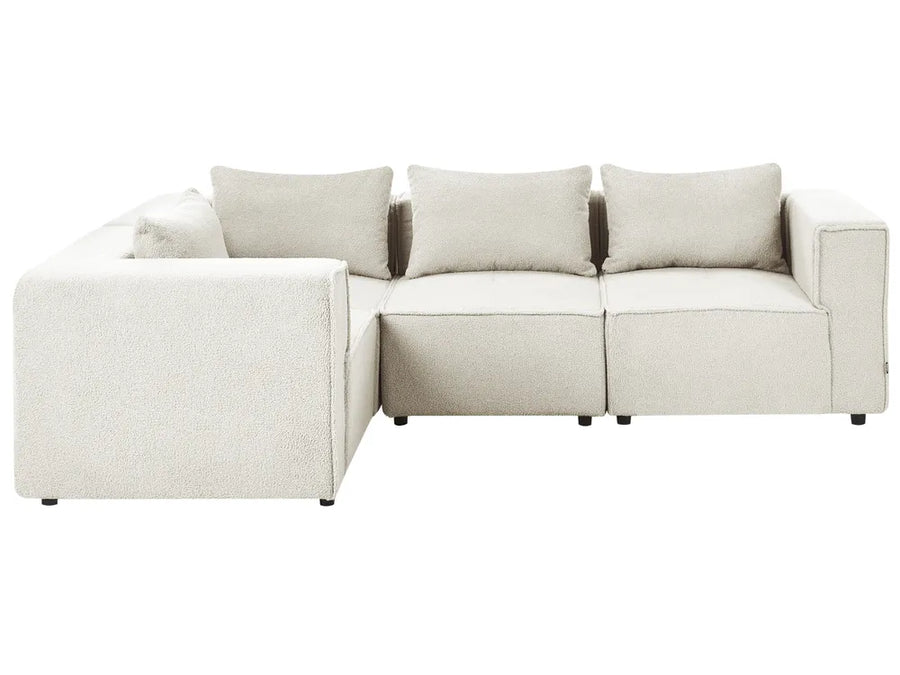 A modern modular sectional sofa upholstered in a light beige textured fabric, featuring a left-facing chaise lounge and four matching back cushions, shown against a plain white background.