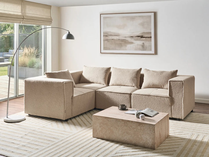 Beige sectional sofa in a living room with a coffee table and decorative items.