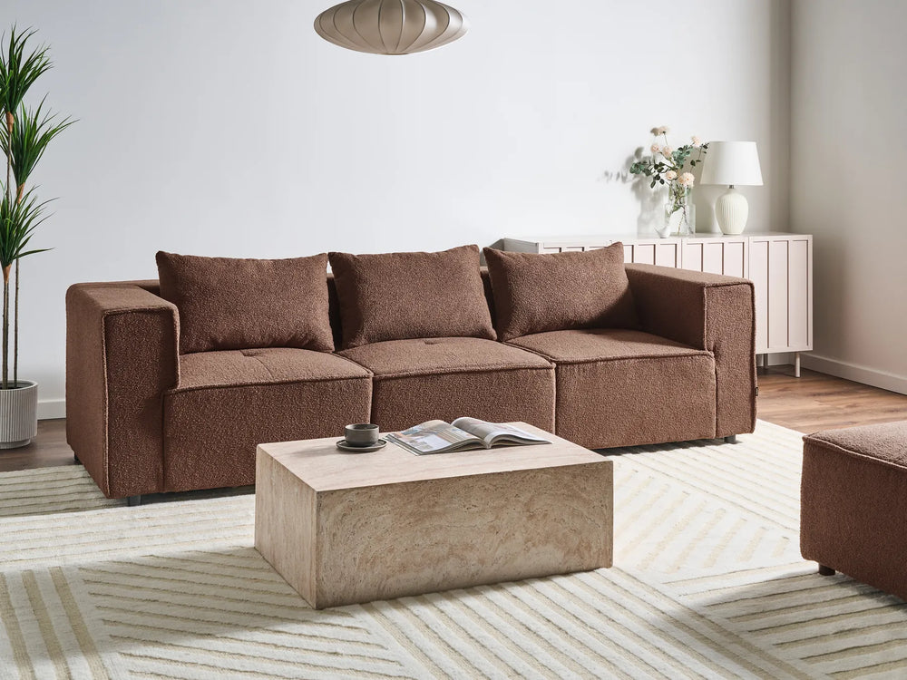 Brown sectional sofa in a living room with a coffee table and decorative items.