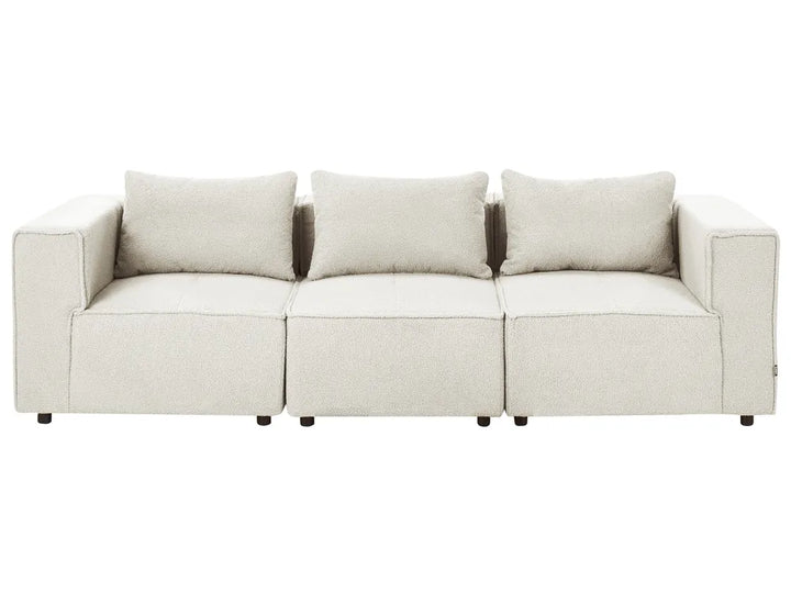 A modern three-seater sofa upholstered in a light beige textured fabric, featuring three matching back cushions and dark wooden legs, shown against a plain white background.