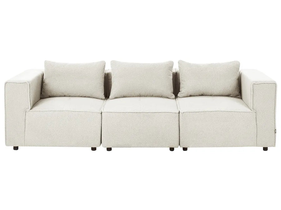 A modern three-seater sofa upholstered in a light beige textured fabric, featuring three matching back cushions and dark wooden legs, shown against a plain white background.