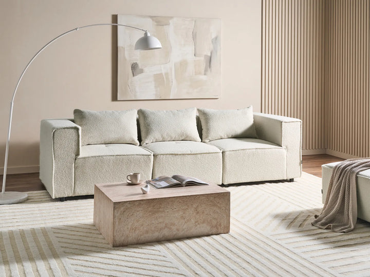 Beige sofa in a living room with a coffee table and decorative items.