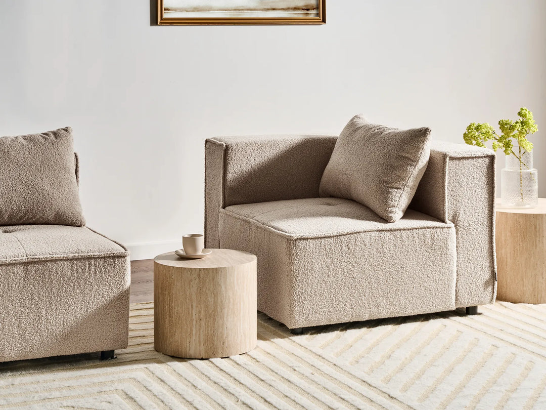 Beige sectional sofa in a living room setting with a side table and decorative elements.