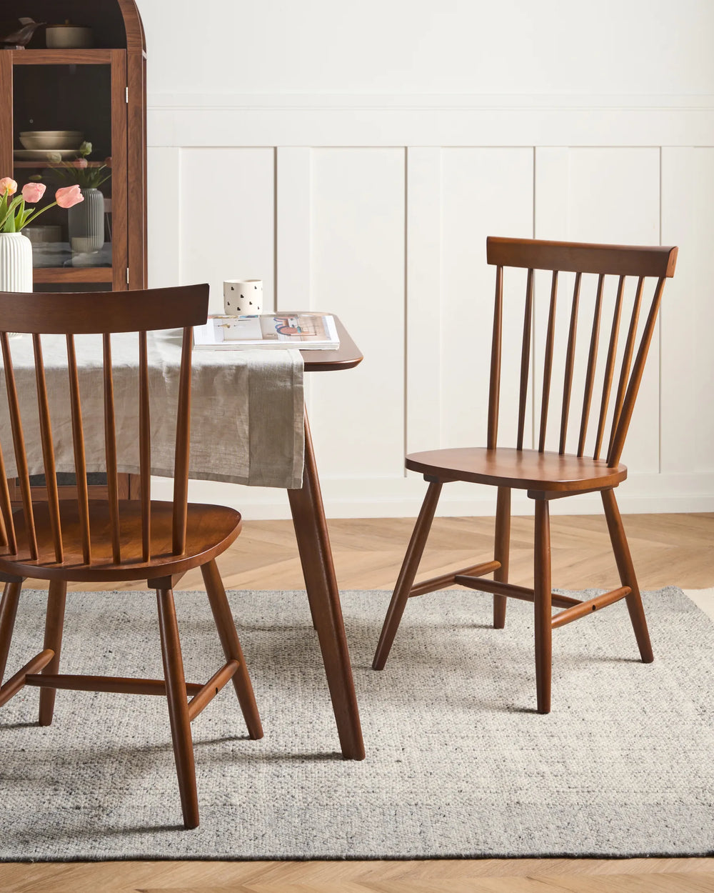 Wooden dining chairs around a table with a neutral decor background