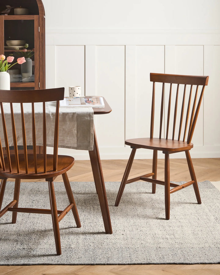 Wooden dining chairs around a table with a neutral decor background
