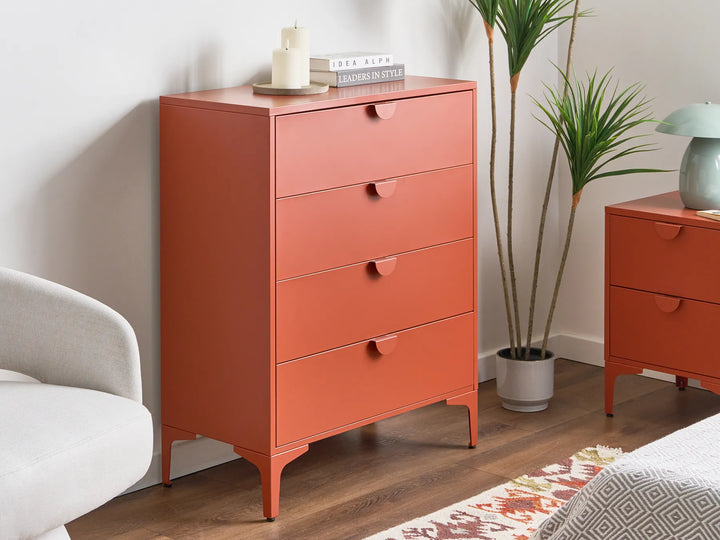 Orange dresser with three drawers in a room setting with a plant and chair.