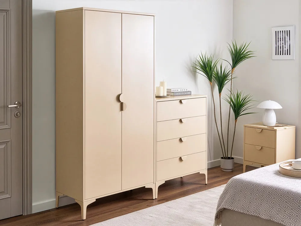 A light beige bedroom furniture set including a tall double-door wardrobe, a four-drawer chest, and a smaller side table, styled in a modern bedroom next to a bed and potted plants.