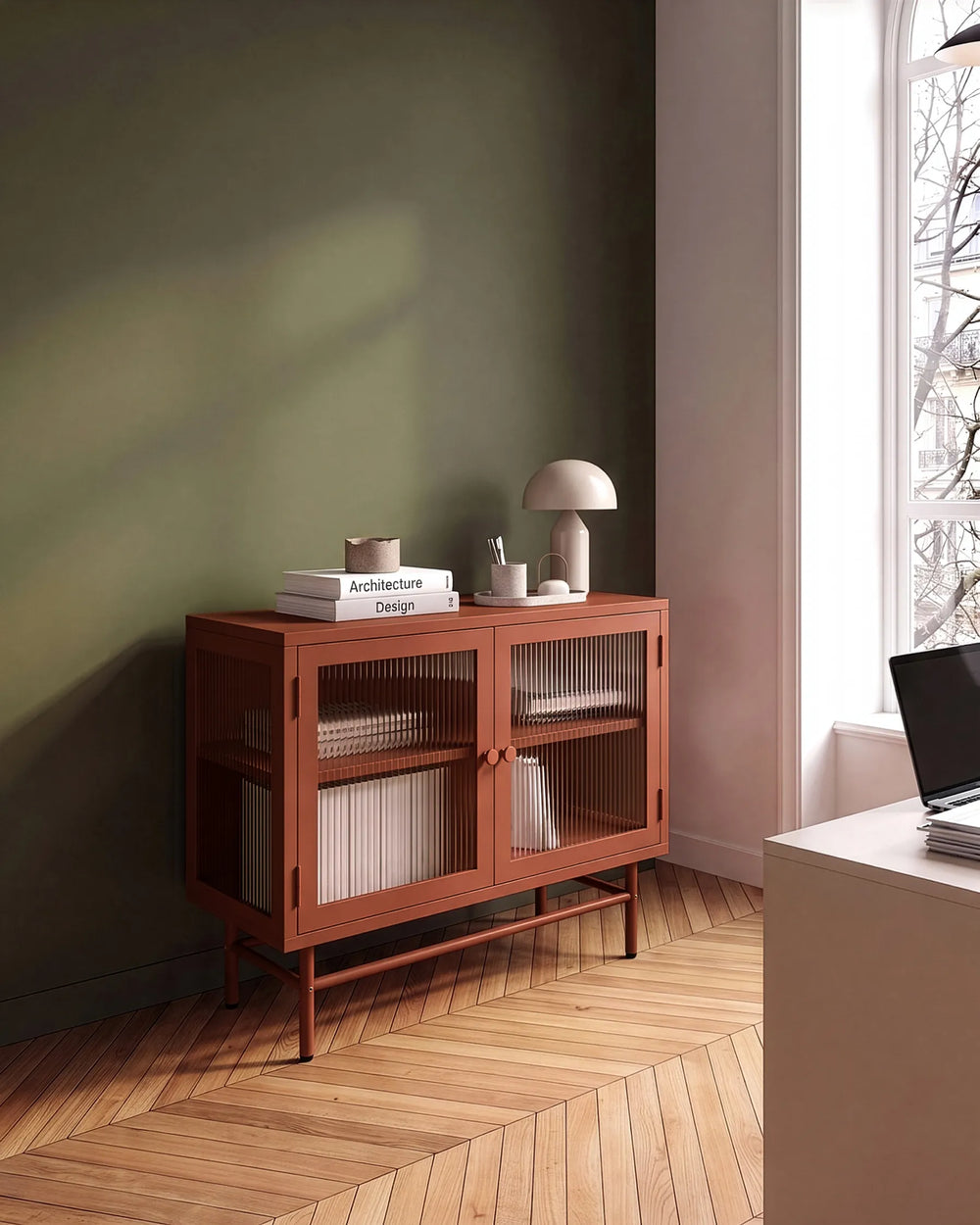 A mid-century modern wooden sideboard cabinet with two glass-paneled doors, styled in a minimalist room with a dark green wall, herringbone wood floor, and a window.