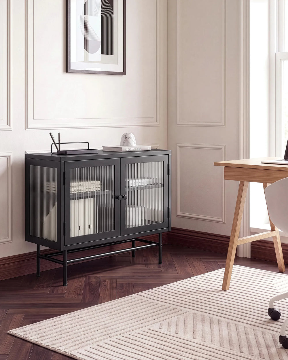 A modern black metal sideboard cabinet with two ribbed glass doors, styled in a home office setting next to a wooden desk and chair.