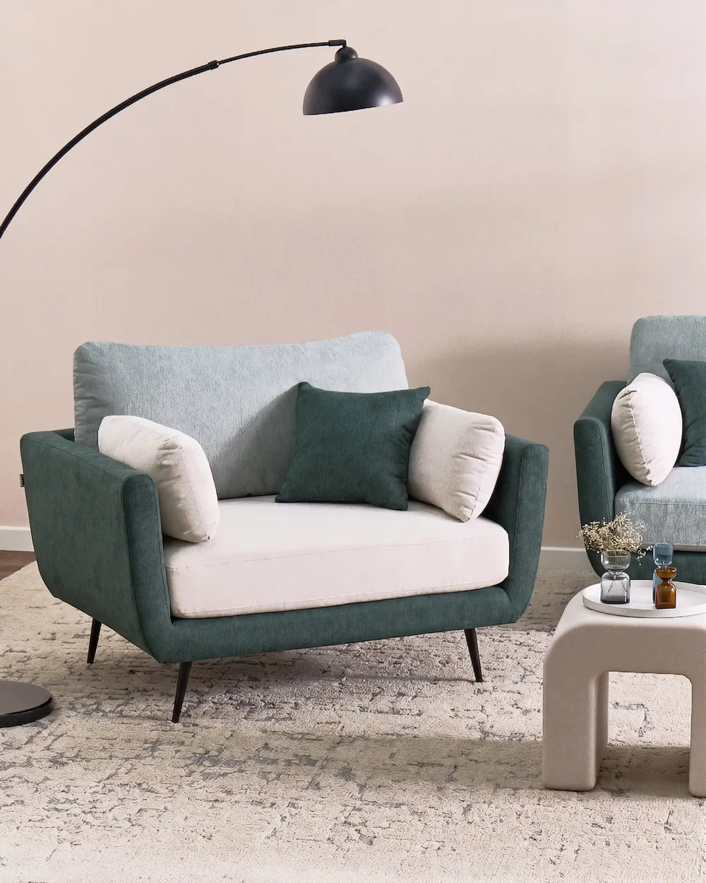 Modern living room with a teal sofa and matching armchair, featuring decorative pillows and a floor lamp.