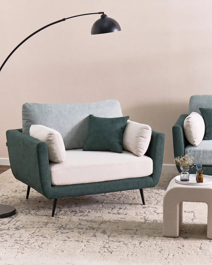 Modern living room with a teal sofa and matching armchair, featuring decorative pillows and a floor lamp.