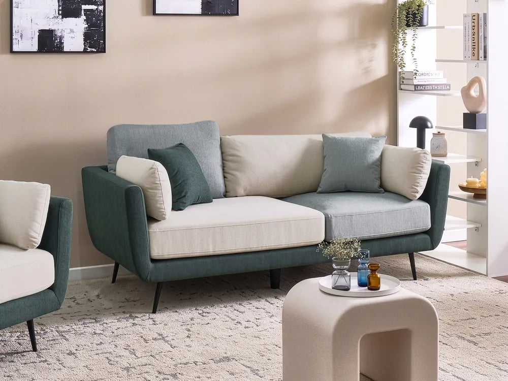 A modern two-seater sofa in teal green and cream upholstery, styled in a contemporary living room setting with matching accent pillows, a textured rug, and a small white side table.