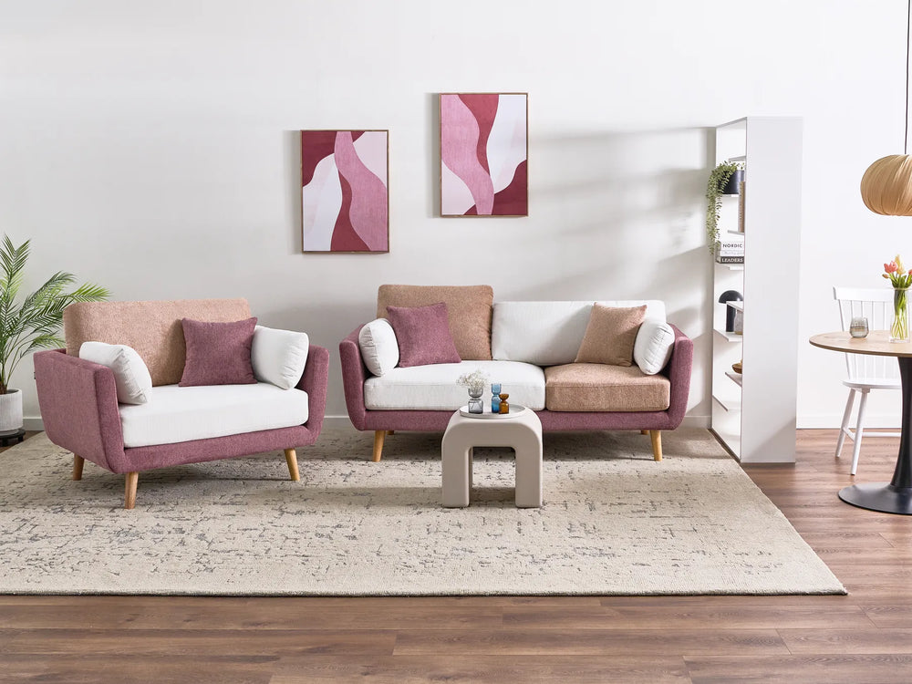 A modern living room setup featuring a mauve-pink and white armchair, a matching three-seater sofa, and a small square side table on a beige rug over dark wood flooring.