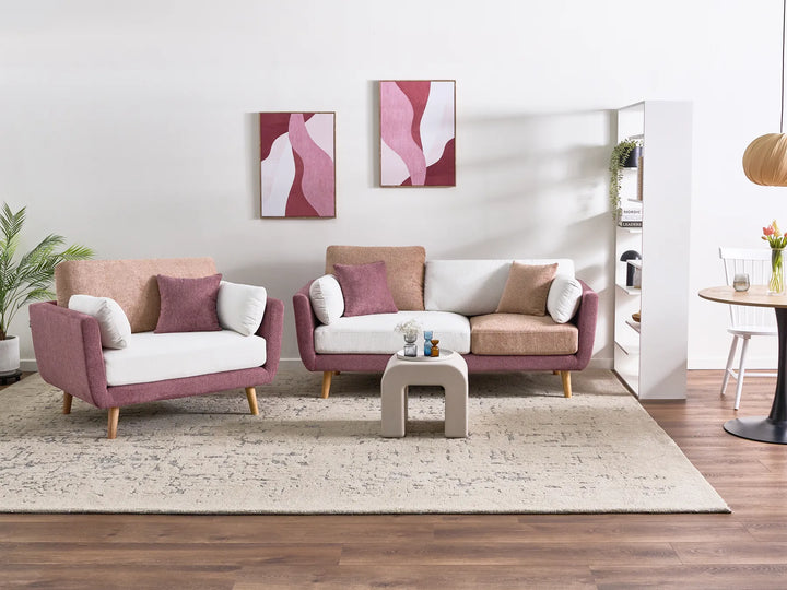 A modern living room setup featuring a mauve-pink and white armchair, a matching three-seater sofa, and a small square side table on a beige rug over dark wood flooring.