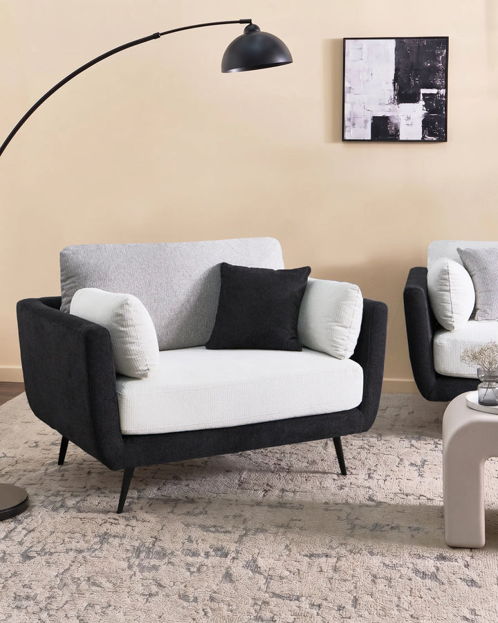 Modern living room with a black and gray sofa, floor lamp, and abstract art on the wall.