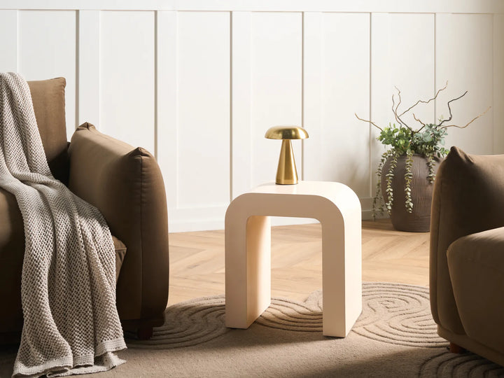 Modern living room with a beige armchair, white side table, and decorative elements.